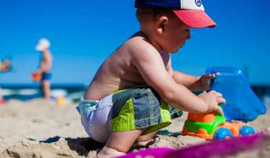 Sonne ist lebensnotwenig - Junge spielt im Sand.